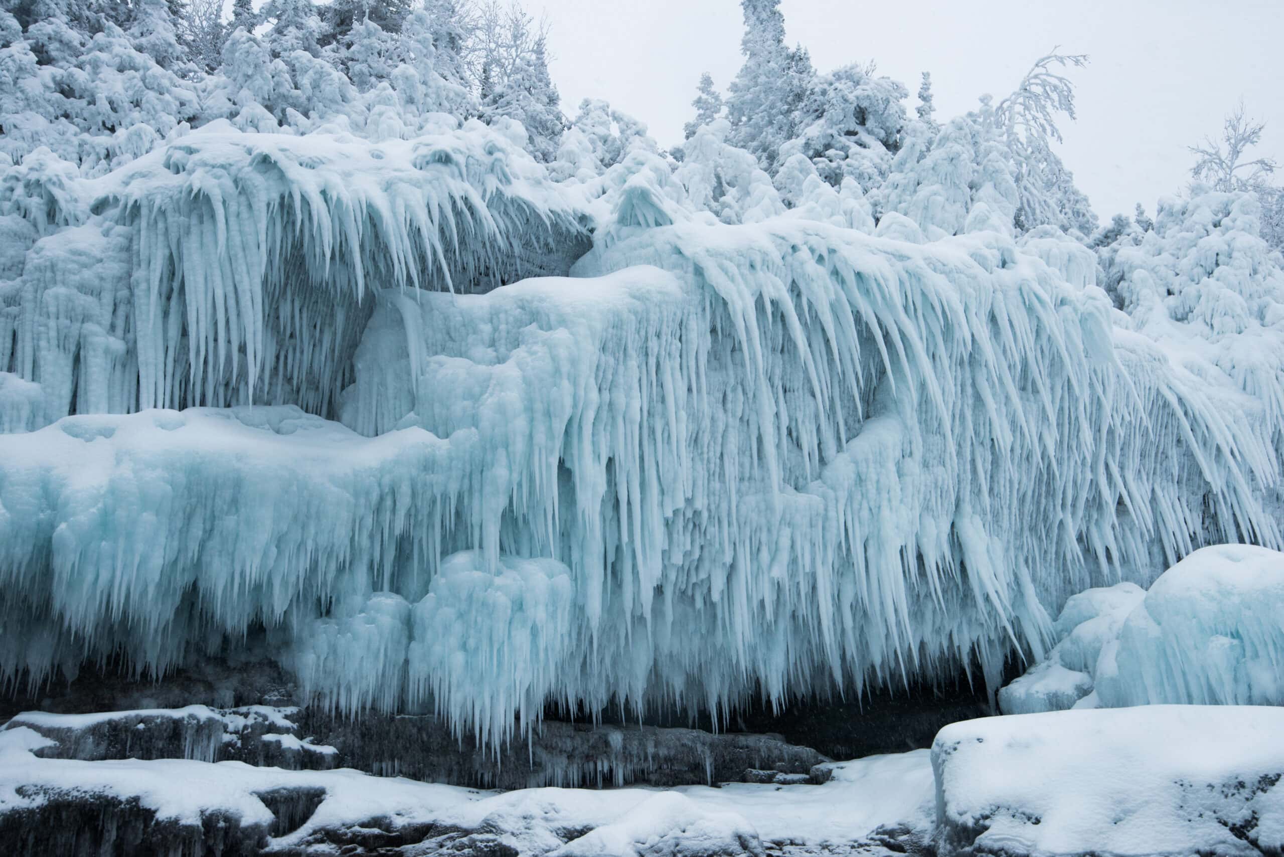 Hundreds of ice daggers drape over a shore-side cliff