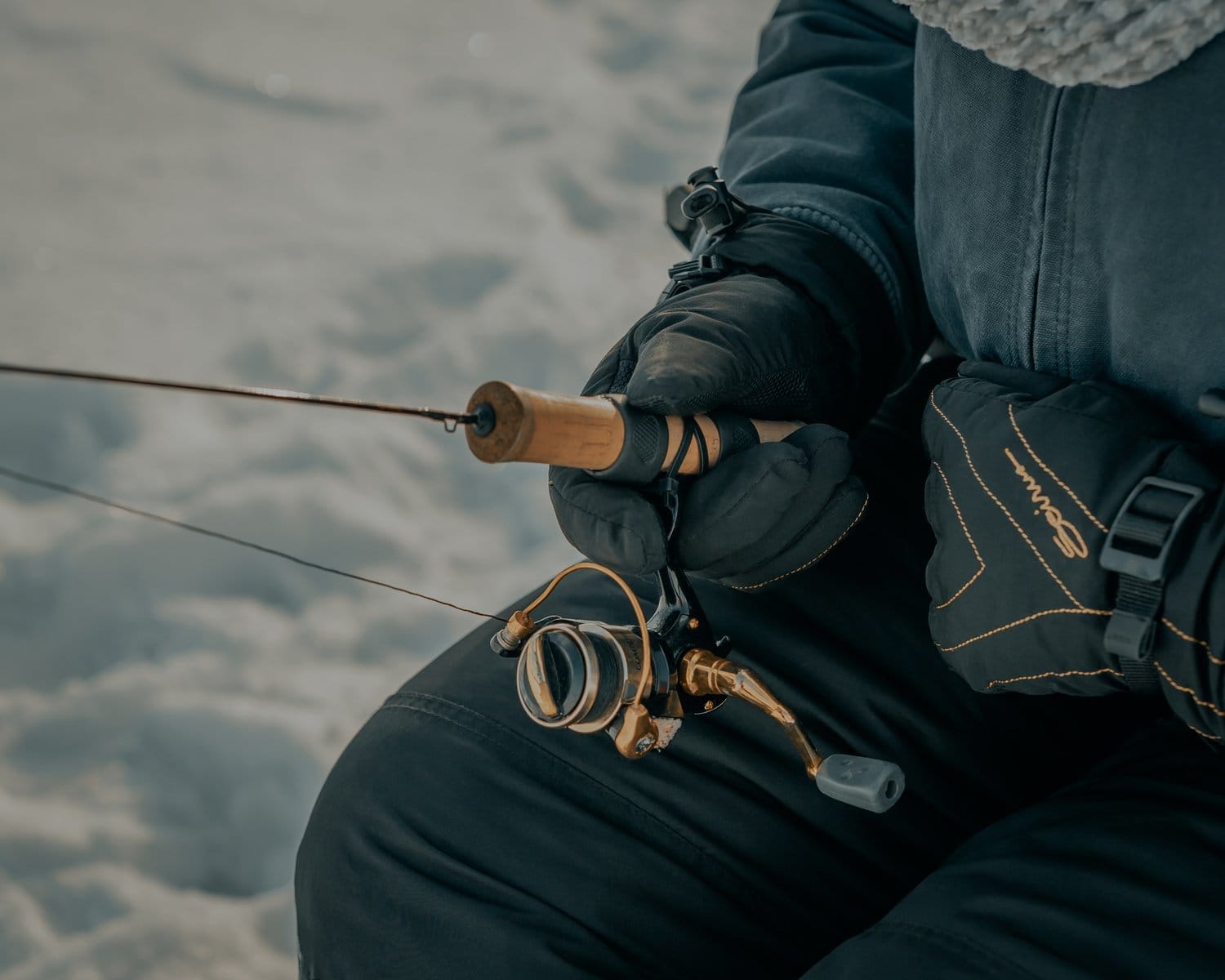 Close-up of gloved hands holding a fishing pole.